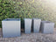 Collection of Tall Modern Tapered Fiberglass Gray Planters and Square Gray Planters Outdoors
